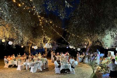 Dîner en plein air sous des guirlandes lumineuses et lanternes, avec des invités assis à des tables décorées.