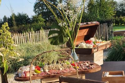 Plateau de charcuterie et fromages avec légumes frais, disposé sur une table en extérieur près d'un jardin.