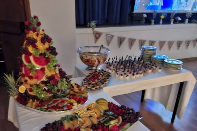 Traiteur Brusyl - Open K Fe Saint-Martin-le-Vinoux #4 Buffet avec une pyramide de fruits frais, une salade de fruits, des verrines, des tartelettes et des assiettes empilées.