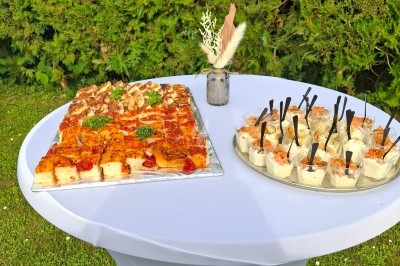 Traiteur Brusyl - Open K Fe Saint-Martin-le-Vinoux #2 Plateau de bouchées salées et verrines disposé sur une table blanche en extérieur, avec un vase décoratif.