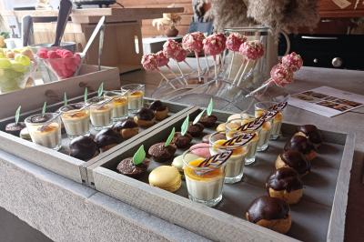 Plateau de desserts variés comprenant verrines, macarons, choux au chocolat et sucettes décorées sur une table en bois.