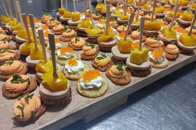 Plateau de canapés variés avec mousse, œufs de poisson, fromage et garnitures colorées sur un plan de travail.