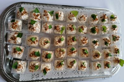 Plateau en métal contenant des verrines de mousse garnies de miettes de noix et de feuilles de menthe.