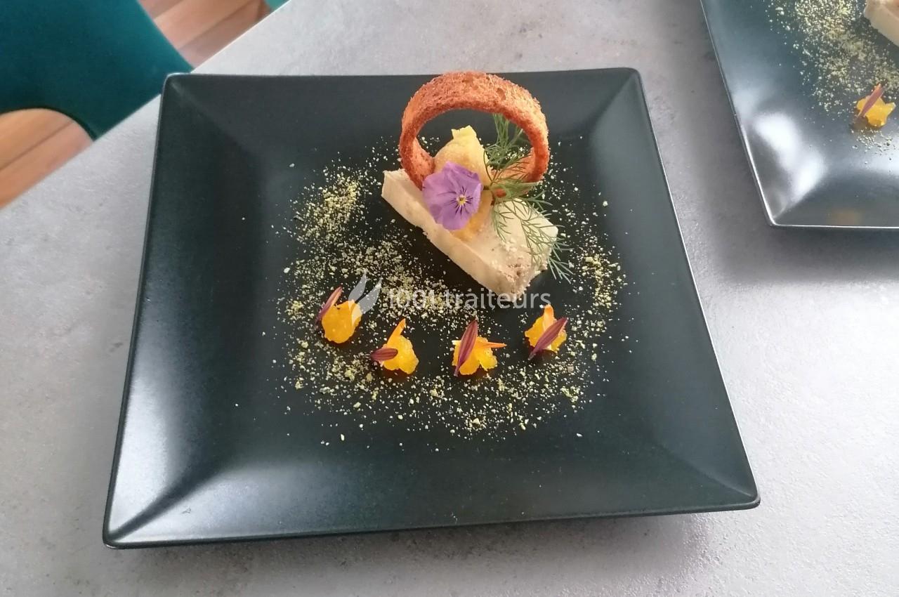 Dessert dressé sur une assiette noire, avec mousse, fleurs comestibles, croustillant et décorations colorées.