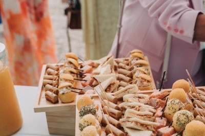 Plateaux en bois garnis de canapés variés, mini-sandwichs et amuse-bouches lors d'un événement en plein air.
