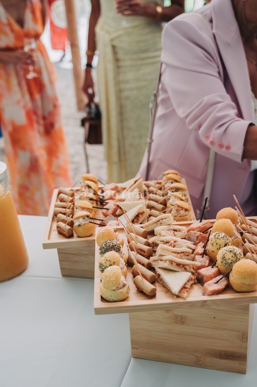 Plateaux en bois garnis de canapés variés, mini-sandwichs et amuse-bouches lors d'un événement en plein air.