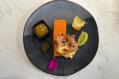 Assiette gastronomique avec saumon, pain croustillant, caviar, sauce, physalis, citron vert et pétale de fleur.