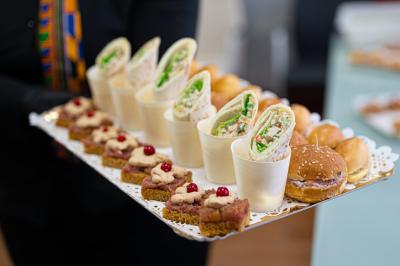 Plateau de bouchées apéritives comprenant wraps, mini-burgers et toasts garnis, présenté sur un support décoratif.