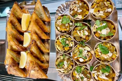 Assortiment de samoussas dorés avec des quartiers de citron et petits bols garnis de fruits secs et herbes fraîches.