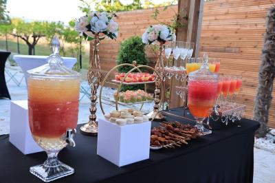 Traiteur Les Saveurs de Anna Traiteur Décines-Charpieu #3 Table de buffet en extérieur avec boissons, verrines, macarons, brochettes et décorations florales élégantes.