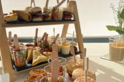 Buffet de mini-burgers, verrines, quiches et autres amuse-bouches disposés sur des plateaux en bois.