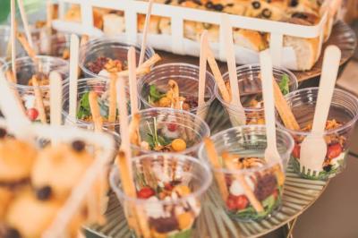 Des verrines garnies de légumes frais, gressins et noix, disposées sur une table avec des pains en arrière-plan.