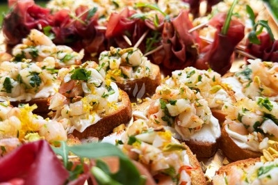 Assortiment de bouchées apéritives avec tartines garnies de crevettes et herbes fraîches, accompagnées de roulés de jambon.