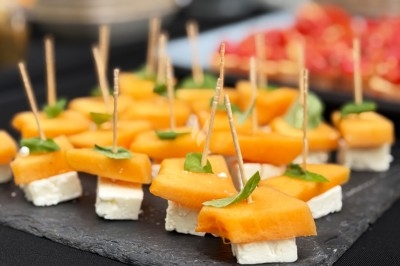 Traiteur Chica et Cocco Saint-Germain-en-Laye #5 Bouchées apéritives composées de cubes de feta, morceaux de melon et feuilles de basilic, présentées sur un plateau ardoise.