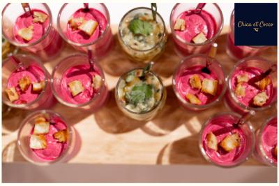 Verrines de mousse rose garnies de croûtons et d'herbes, entourant une verrine centrale au contenu crémeux.