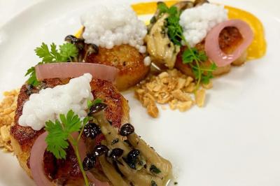 Assiette de noix de Saint-Jacques poêlées, garnies de perles, champignons, pickles et herbes sur une purée.