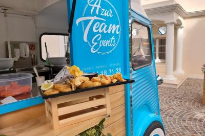 Plateau de beignets dorés avec un quartier de citron, posé sur une caisse en bois devant un food truck bleu.
