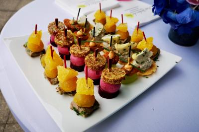 Assortiment de bouchées colorées sur un plateau blanc, disposées sur une table avec une nappe blanche.