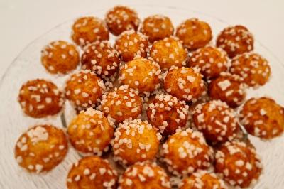 Assortiment de chouquettes dorées garnies de sucre perlé, disposées sur une assiette transparente.
