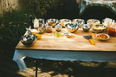 Table en bois avec divers bols, pots et ingrédients disposés pour la préparation culinaire en extérieur.