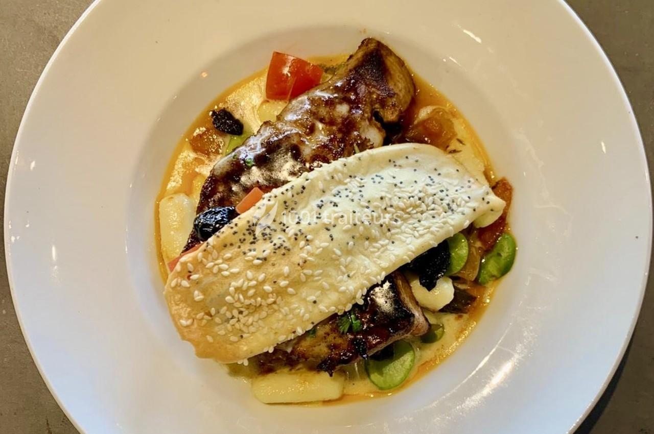 Traiteur Traiteur une Faim d'Apprendre Lyon 9 #1 Plat servi dans une assiette blanche, composé de viande gratinée, légumes, sauce et une pâte garnie de graines.