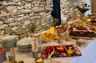 Traiteur Traiteur une Faim d'Apprendre Lyon 9 #3 Table garnie de plats variés, incluant charcuterie, pains, légumes et desserts, disposée devant un mur en pierre.