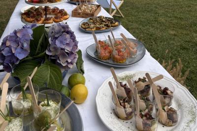 Traiteur Concept Catering Events Cannes #2 Buffet en plein air avec divers plats et verrines sur une table blanche, décorée d'hortensias et de citrons.