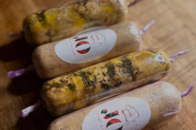 Quatre rouleaux de préparation alimentaire emballés sous vide, posés sur une surface en bois.