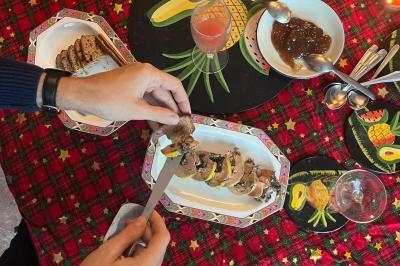 Une personne tartine une tranche de pain avec du foie gras sur une table décorée pour les fêtes.