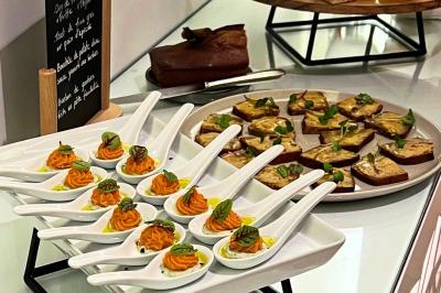 Cuillères apéritives garnies de mousse orange et herbes fraîches, accompagnées de toasts sur un plateau.