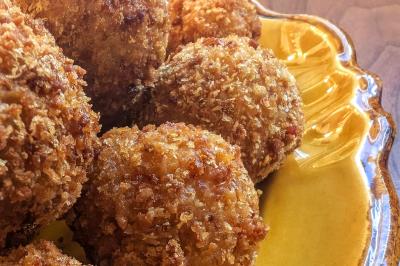 Boulettes panées dorées servies sur une assiette jaune en gros plan.