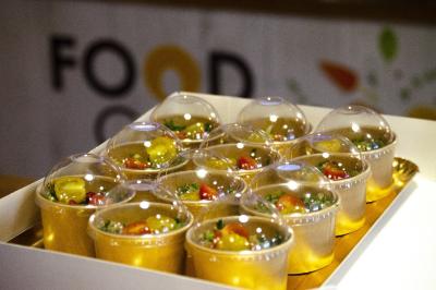 Douze verrines transparentes contenant une salade colorée, présentées dans un plateau blanc.