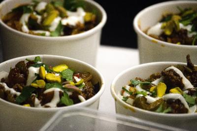 Quatre bols garnis de légumes, sauce blanche, pistaches et herbes fraîches, disposés sur une table.