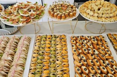 Buffet de pièces apéritives variées disposées sur des plateaux, incluant canapés, bouchées et amuse-bouches.