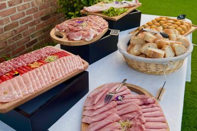 buffet froid Plateau de charcuterie variée, pain et petits pains disposés sur une table blanche en extérieur.