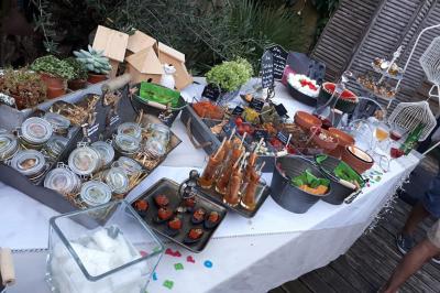 Traiteur Ardélices Buffet Breuillet #2 Buffet varié en extérieur avec verrines, plats colorés, boissons et décorations végétales sur une table blanche.