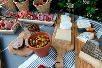 Traiteur Ardélices Buffet Breuillet #5 Plateau de fromages variés, charcuteries, olives et tomates cerises disposés sur une table avec nappes et paniers en arrière…