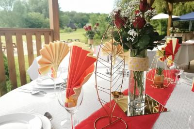 Traiteur Iles en Fete Magny-les-Hameaux #5 Table décorée pour un événement avec nappes blanches, chemin de table rouge, fleurs et pliages de serviettes colorés.