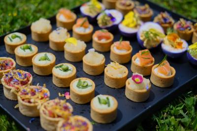 Buffets Cocktails Plateau de bouchées apéritives variées disposées sur un fond d'herbe, comprenant tartelettes et garnitures colorées.