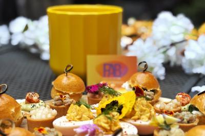 Buffets Cocktails Plateau de bouchées apéritives variées avec fleurs comestibles, présenté sur une table avec un pot jaune en arrière-plan.