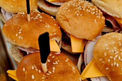 Mini burgers garnis de fromage, jambon et piques en bois, disposés dans un plateau en métal.