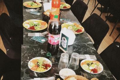 Table dressée avec des assiettes de salades variées, boissons, couverts et serviettes sur une nappe noire.