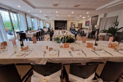 Traiteur Le Quai Fleuri Les Villages Vovéens #5 Salle de réception décorée pour un événement, avec tables dressées, nappes blanches et arrangements floraux centraux.