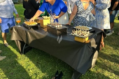 Personnes se servant à un buffet en extérieur, avec des amuse-bouches disposés sur une table recouverte d'une nappe noire.