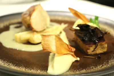 Assiette gastronomique avec viande, purée, asperges, champignons et chips croustillantes, présentée de manière élégante.