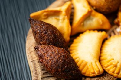 Traiteur La Beyrouthine Roquebrune-Cap-Martin #2 Assortiment de beignets et pâtisseries salées disposés sur un plateau en bois.