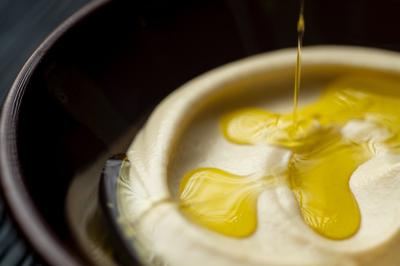 Traiteur La Beyrouthine Roquebrune-Cap-Martin #5 Bol de houmous crémeux avec un filet d'huile d'olive versé en surface.