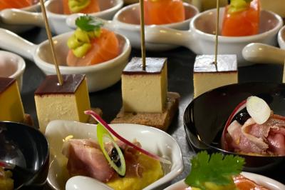Assortiment de bouchées apéritives avec saumon, foie gras et garnitures variées, présentées sur des cuillères et coupelles.