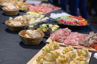 Plateau de buffet avec charcuteries, fromages, crudités, pains et amuse-bouches sur une table noire.