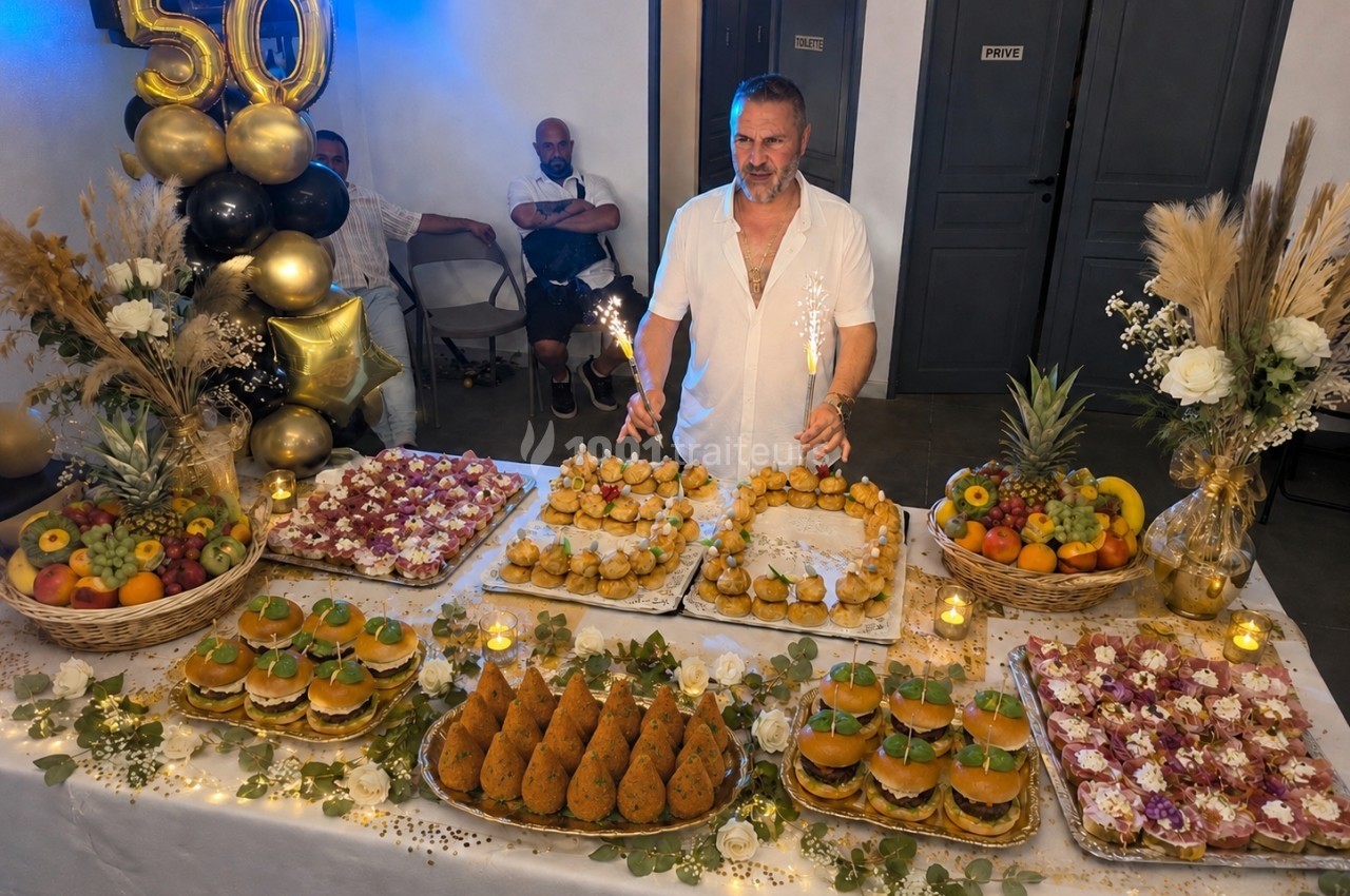 Traiteur Pasta Da Nonna Mia Bouc-Bel-Air #1 Un homme souriant devant une table garnie de plats variés et décorée pour une fête avec des ballons marquant ’50’.